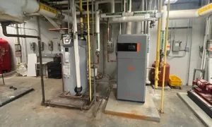 Intellihot’s iE1 tankless CO2 heat pump water heater (at right) installed at Washington, D.C. school; image from Intellihot